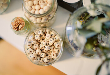 Close up of wooden letter beads and other handicraft articles in glasses. 