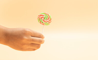 lollipop in a hand isolated on colorful background, front view