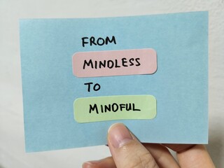 Hand holding a note showing the words From Mindless To Mindful 