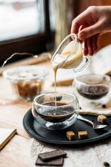 Espresso in a glass cup hand pours condensed milk - cane sugar