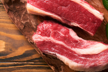 Steak beef. Raw steak New York with rosemary and spices on a piece of parchment paper on old dark wooden background. Top view. Mock up.