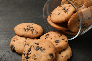 Overturned jar with chocolate chip cookies on black table, closeup