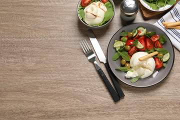 Delicious burrata salad served on wooden table, flat lay. Space for text