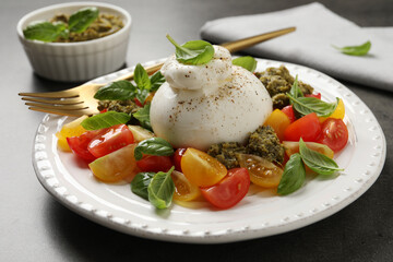 Delicious burrata salad served on grey table, closeup
