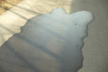 Puddle on asphalt. Wet road. Spilled water on pedestrian zone.