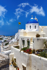 Fototapeta na wymiar White church with a blue dome on Santorini island in Greece. Hot summer sun day.