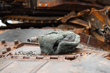 War in Ukraine. Russian cap with earflaps lies on a burnt tank.