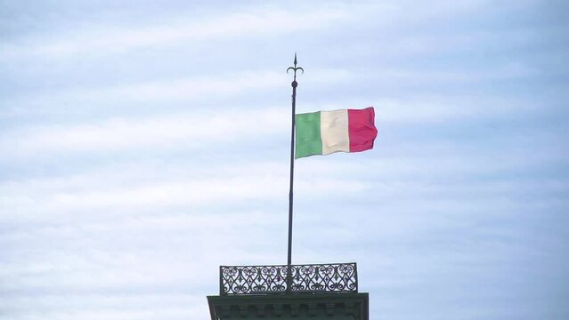 Slow motion shot of the Italian flag waving on a flag pole on top of a building in the Piazza Unita d'Italia in Trieste, Italy
