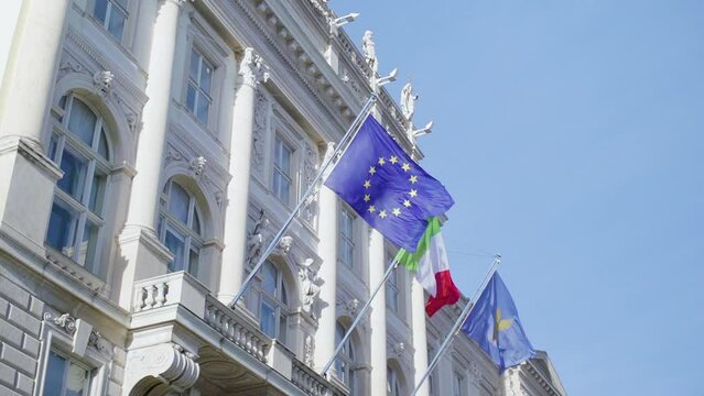 Slow motion shot of the flags of the European Union and Italy hanging on a building in the Piazza Unita d'Italia in Trieste, Italy
