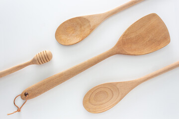 Wooden kitchen tools, spoon, honey-spoon and spatula, top view shot on white background.