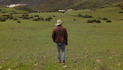 Rear view of adult man in cowboy hat on field