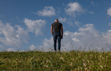 Naklejka na ściany i meble Full length of adult man standing on grass against cloudy sky
