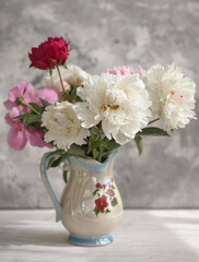Fototapeta na wymiar Still life with white and pink peonies in a white vase