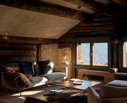 Mountain chalet living room with large sofa, two armchairs and a large window overlooking the Alps