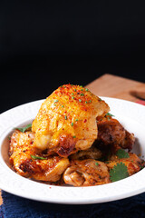 Food concept Roasted spicy chicken thighs on ceramic plate on wooden board with black background with copy space