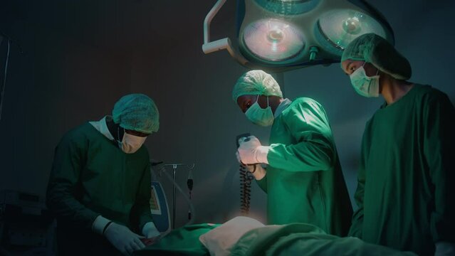 Professional doctors in the operating room making  CPR and use defibrillator electrical device to saving a patient life. health care concept.