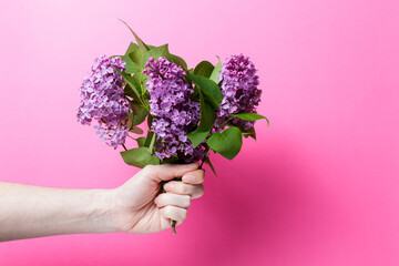 girl holding a bouquet of lilacs on a pink background