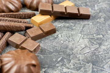 Pieces of bitter, dark and milk chocolate, marmalade and marshmallows in chocolate cocoa glaze on a black background. Space for the text.