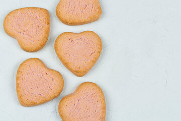 Beautiful butter cookies in the shape of a heart on a gray concrete background close-up. Space for text. Recipe, ingredients. Birthday, valentine's day, good morning. Romance and love