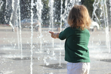 Child stand and play on street fountain on Philadelphia square over sunset near city hall in downtown