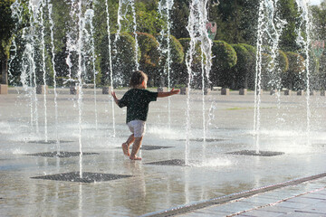 A child runs near a fountain on a summer day
