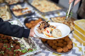 Selective focus shot of food being served on paper plate during hari raya party in Kuala Lumpur,...