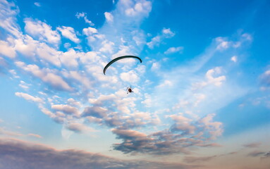 Paraglider on the background of blue sky with white clouds in summer