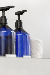 Blue soap dispenser with a white towel on a gray background. Cosmetics and skin care