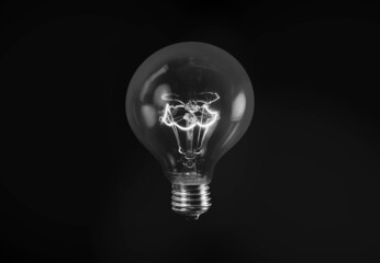 Black and white photo of tungsten light bulb isolated on black background 