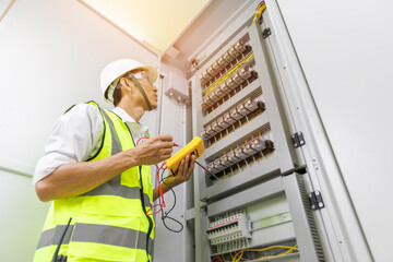 Electrical engineer or repairman holding digital multimeter to inspecting the electrical system in...