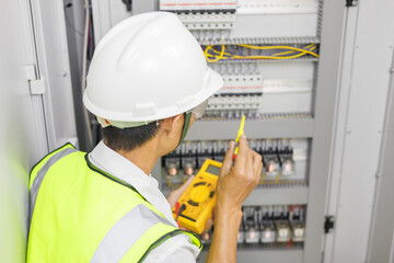Electrical engineer or repairman holding digital multimeter to inspecting the electrical system in a factory.