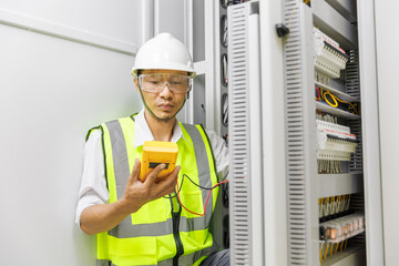 Electrical engineer or repairman holding digital multimeter to inspecting the electrical system in...