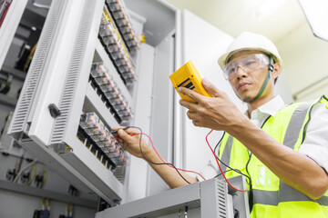 Electrical engineer or repairman holding digital multimeter to inspecting the electrical system in...