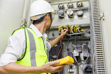 Electrical engineer or repairman holding digital multimeter to inspecting the electrical system in a factory.