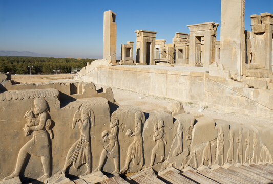 Bas-relief decoration along stairs from Darius palace to Palace of Xerxes, ruins of Daraius palace in the background, Persepolis, Pesia, Iran.