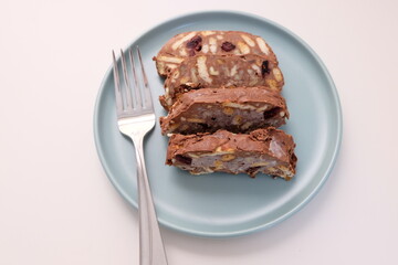 Homemade mosaic chocolate biscuit cake served in a blue plate, selective focus. It is called 
