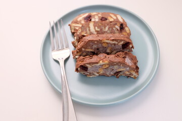 Homemade mosaic chocolate biscuit cake served in a blue plate, selective focus. It is called 