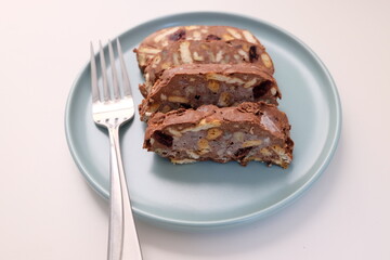 Homemade mosaic chocolate biscuit cake served in a blue plate, selective focus. It is called 