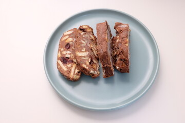 Homemade mosaic chocolate biscuit cake served in a blue plate, selective focus. It is called 