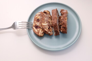 Homemade mosaic chocolate biscuit cake served in a blue plate, selective focus. It is called 