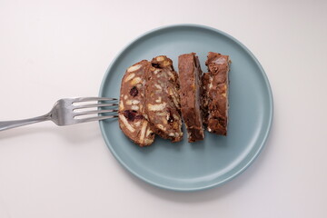 Homemade mosaic chocolate biscuit cake served in a blue plate, selective focus. It is called "Mozaik Pasta" in Turkish. That is texture of it not grain. Traditional Turkish dessert.