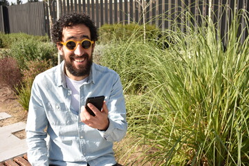 Feliz hombre joven usando smartphone en espacio exterior. Hipster