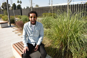 Joven sorprendido ganando dinero invirtiendo desde el parque. Concepto nómada digital.