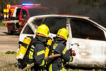 Feuerwehrmänner löschen ein brennendes Auto
