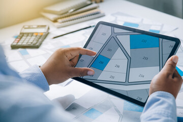 Man holding a tablet looking at lots of lands. Land plot management - real estate concept with...