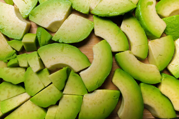 Avocado slices on a wooden board, top view