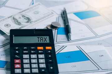 calculator with words taxes, banknotes, coins, pens, placed on land documents. The concept for residential construction, and development. home or house for sale, buy, investment.
