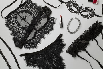 Set of black sexy lace lingerie with accessories on color background, top view