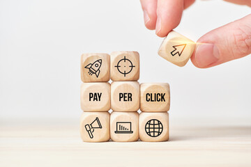 Concept Pay per click or PPC. Person stacks wooden cubes from text and icons. - obrazy, fototapety, plakaty