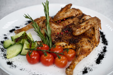 Grilled fried Chicken Tabaka and fresh vegetables on white plate